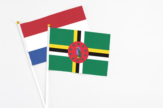 Dominica and Netherlands stick flags on white background. High quality fabric, miniature national flag. Peaceful global concept.White floor for copy space.