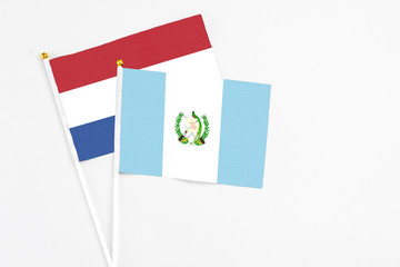Guatemala and Netherlands stick flags on white background. High quality fabric, miniature national flag. Peaceful global concept.White floor for copy space.