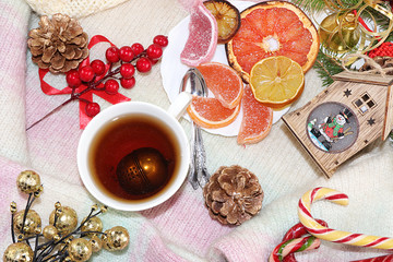 Christmas or New Year background with fir branches, lemon and tea on the background of Christmas decorations, a warm woolen sweater, flat lay, top view, selective focus