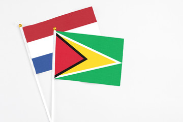 Guyana and Netherlands stick flags on white background. High quality fabric, miniature national flag. Peaceful global concept.White floor for copy space.