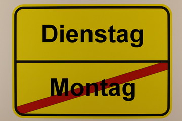 Grafische Darstellung der Wochentage Montag und Dienstag auf einem Ortsschild