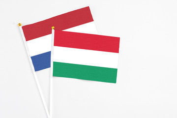 Hungary and Netherlands stick flags on white background. High quality fabric, miniature national flag. Peaceful global concept.White floor for copy space.