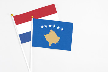 Kosovo and Netherlands stick flags on white background. High quality fabric, miniature national flag. Peaceful global concept.White floor for copy space.