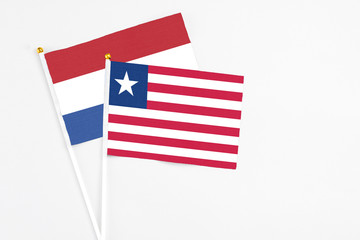 Liberia and Netherlands stick flags on white background. High quality fabric, miniature national flag. Peaceful global concept.White floor for copy space.