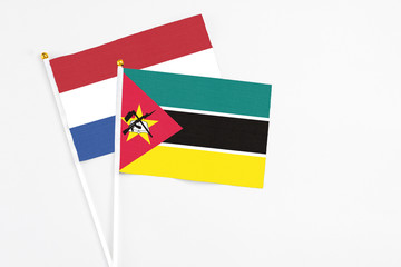 Mozambique and Netherlands stick flags on white background. High quality fabric, miniature national flag. Peaceful global concept.White floor for copy space.