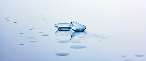 Contact lenses and water drops on light blue background. Eyewear, eyesight, eye care and health, ophthalmology and optometry
