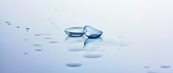 Contact lenses and water drops on light blue background. Eyewear, eyesight, eye care and health,...