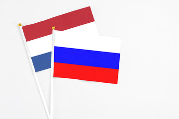 Russia and Netherlands stick flags on white background. High quality fabric, miniature national flag. Peaceful global concept.White floor for copy space.
