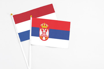 Serbia and Netherlands stick flags on white background. High quality fabric, miniature national flag. Peaceful global concept.White floor for copy space.