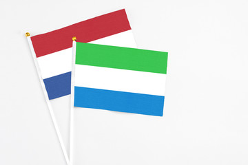 Sierra Leone and Netherlands stick flags on white background. High quality fabric, miniature national flag. Peaceful global concept.White floor for copy space.