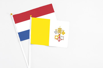 Vatican City and Netherlands stick flags on white background. High quality fabric, miniature national flag. Peaceful global concept.White floor for copy space.
