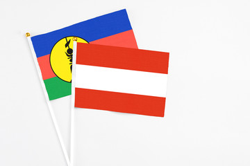 Austria and New Caledonia stick flags on white background. High quality fabric, miniature national flag. Peaceful global concept.White floor for copy space.