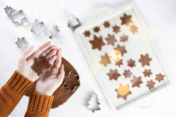 A womens hands hold a gingerbread a snowflakes cookie on a white background. Flat lay cooking.