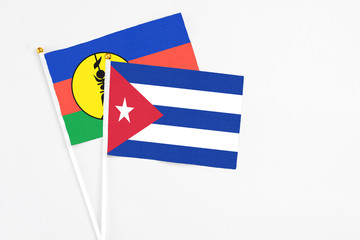 Cuba and New Caledonia stick flags on white background. High quality fabric, miniature national flag. Peaceful global concept.White floor for copy space.