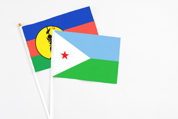 Djibouti and New Caledonia stick flags on white background. High quality fabric, miniature national flag. Peaceful global concept.White floor for copy space.