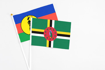Fototapeta premium Dominica and New Caledonia stick flags on white background. High quality fabric, miniature national flag. Peaceful global concept.White floor for copy space.