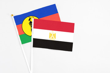 Egypt and New Caledonia stick flags on white background. High quality fabric, miniature national flag. Peaceful global concept.White floor for copy space.