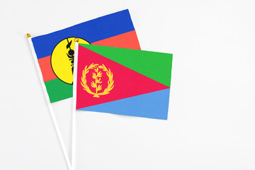 Eritrea and New Caledonia stick flags on white background. High quality fabric, miniature national flag. Peaceful global concept.White floor for copy space.