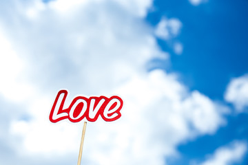 paper cut word love on stick on blue sky background