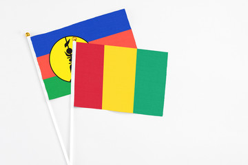 Guinea and New Caledonia stick flags on white background. High quality fabric, miniature national flag. Peaceful global concept.White floor for copy space.