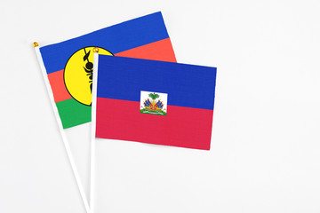 Haiti and New Caledonia stick flags on white background. High quality fabric, miniature national...