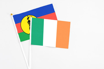 Ireland and New Caledonia stick flags on white background. High quality fabric, miniature national flag. Peaceful global concept.White floor for copy space.