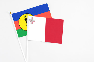 Malta and New Caledonia stick flags on white background. High quality fabric, miniature national flag. Peaceful global concept.White floor for copy space.