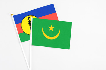 Mauritania and New Caledonia stick flags on white background. High quality fabric, miniature national flag. Peaceful global concept.White floor for copy space.