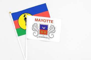 Mayotte and New Caledonia stick flags on white background. High quality fabric, miniature national flag. Peaceful global concept.White floor for copy space.