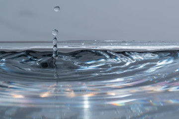 Wassertropfen fallen in das klare Wasser mit kleinen Wellen