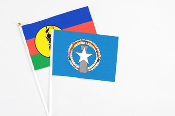 Northern Mariana Islands and New Caledonia stick flags on white background. High quality fabric, miniature national flag. Peaceful global concept.White floor for copy space.