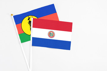 Paraguay and New Caledonia stick flags on white background. High quality fabric, miniature national flag. Peaceful global concept.White floor for copy space.
