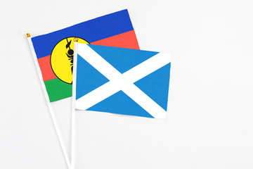 Scotland and New Caledonia stick flags on white background. High quality fabric, miniature national flag. Peaceful global concept.White floor for copy space.