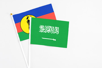 Saudi Arabia and New Caledonia stick flags on white background. High quality fabric, miniature national flag. Peaceful global concept.White floor for copy space.