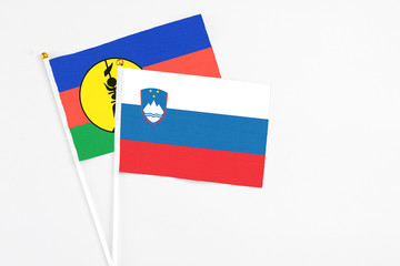 Slovenia and New Caledonia stick flags on white background. High quality fabric, miniature national flag. Peaceful global concept.White floor for copy space.