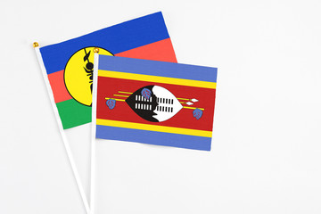Swaziland and New Caledonia stick flags on white background. High quality fabric, miniature national flag. Peaceful global concept.White floor for copy space.