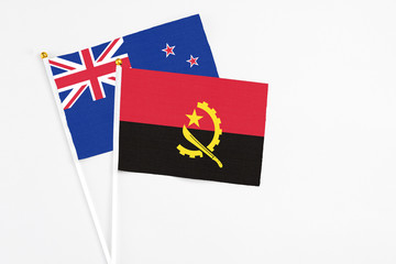 Angola and New Zealand stick flags on white background. High quality fabric, miniature national flag. Peaceful global concept.White floor for copy space.