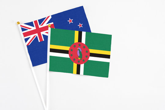 Dominica and New Zealand stick flags on white background. High quality fabric, miniature national flag. Peaceful global concept.White floor for copy space.