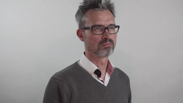 Attraktiver Mittvierziger mit Brille und Dreitagebart dreht sich langsam um und blickt in die Kamera