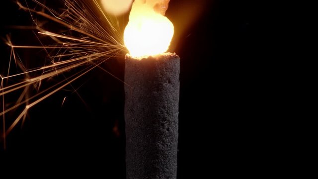 Macro shot of a red hot christmas sparkler burning with golden sparkles while melting a chemical mixture of binders and metal powder.