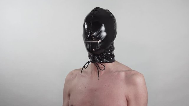 submissive man with latex head mask blinded turning around