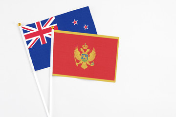 Montenegro and New Zealand stick flags on white background. High quality fabric, miniature national flag. Peaceful global concept.White floor for copy space.