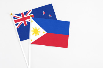 Philippines and New Zealand stick flags on white background. High quality fabric, miniature national flag. Peaceful global concept.White floor for copy space.