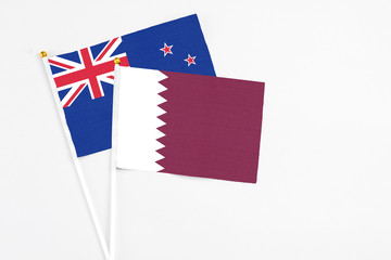 Fototapeta na wymiar Qatar and New Zealand stick flags on white background. High quality fabric, miniature national flag. Peaceful global concept.White floor for copy space.