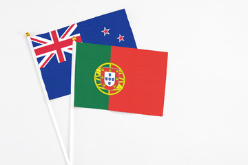 Portugal and New Zealand stick flags on white background. High quality fabric, miniature national flag. Peaceful global concept.White floor for copy space.