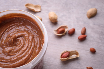 peanut butter and peanuts on grey background , top view