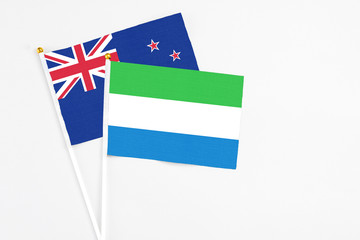 Sierra Leone and New Zealand stick flags on white background. High quality fabric, miniature national flag. Peaceful global concept.White floor for copy space.