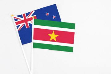 Suriname and New Zealand stick flags on white background. High quality fabric, miniature national flag. Peaceful global concept.White floor for copy space.