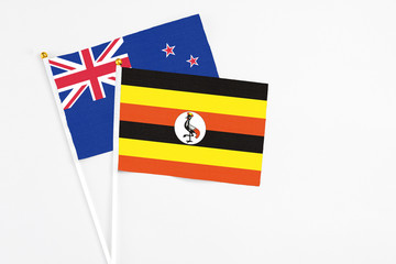 Uganda and New Zealand stick flags on white background. High quality fabric, miniature national flag. Peaceful global concept.White floor for copy space.