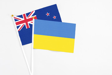 Ukraine and New Zealand stick flags on white background. High quality fabric, miniature national flag. Peaceful global concept.White floor for copy space.
